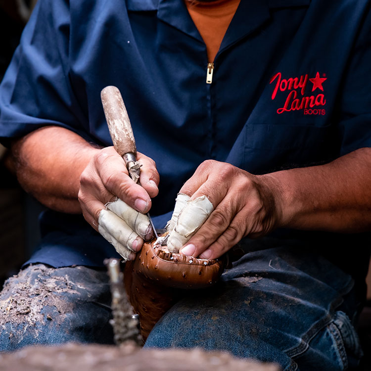 Man works on shoe with tool. 